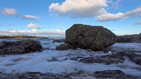 Splashing slow motion waves covering large rock beach boulders Stock Footage 325720828