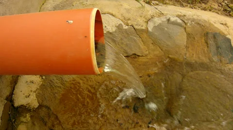 Splashing water from the drain plastic pipe is running down to boulder Stockbeeldmateriaal 39661380