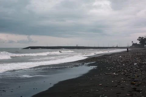 Splashing waves and cloudy sky on a pebble beach in Batumi. Autonomous Republic Stock Photos