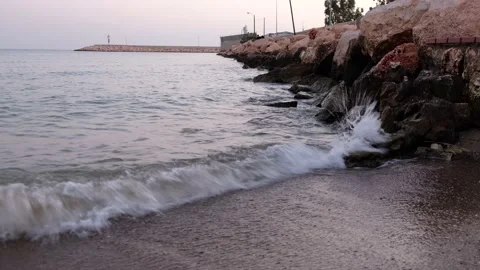Splashing waves and stone pier with lighthouse in the evening Stock Footage 140083714