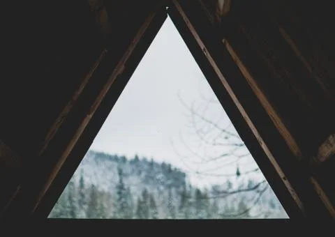 Splendid landscape view through triangular window of a wooden hut by Synevyr  Stock Photos