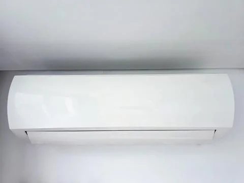 Split air conditioner unit installed indoors against a plain light wall Stock Photos