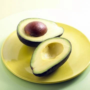 Split avocado on porcelain plates yellow Stock Photos