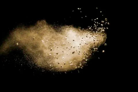 Split debris of brown stone exploding with brown powder against black. Stock Photos