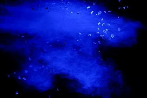 Split debris of stone exploding with blue  powder against black background. Stock Photos