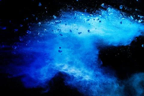 Split debris of  stone exploding with blue powder against black background. Stock Photos