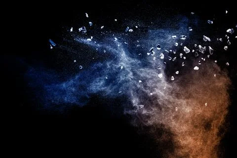 Split debris of  stone exploding with blue powder against black background. Stock Photos