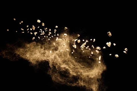 Split debris of stone exploding with brown powder against black background... Stock Photos