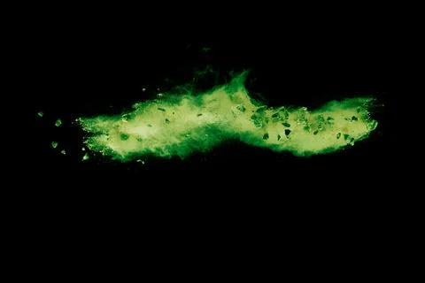 Split debris of  stone exploding with green powder against black background. Stock Photos