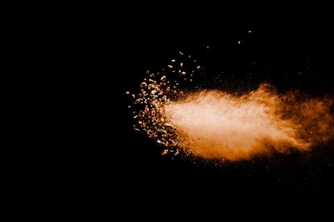 Split debris of stone exploding with orange powder against black background. Foto stock