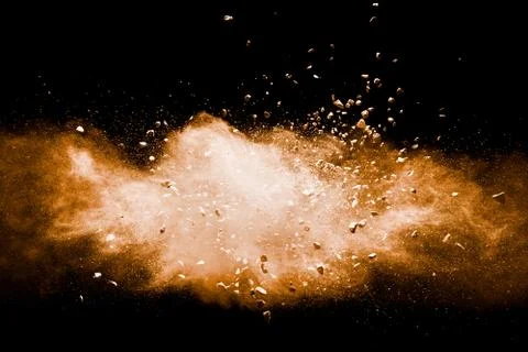 Split debris of stone exploding with orange powder against black background. Stock Photos