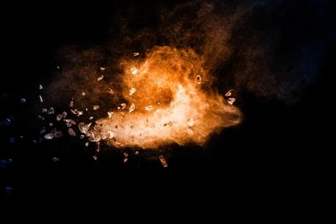 Split debris of stone exploding with orange dust against black background. Stock Photos