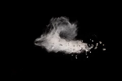 Split debris of stone exploding with white dust against black background. Stock Photos
