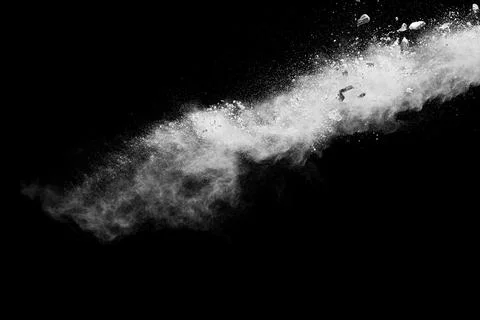 Split debris of stone exploding with white dust against black background. Stock Photos