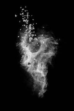 Split debris of stone exploding with white dust against black background. Stock Photos