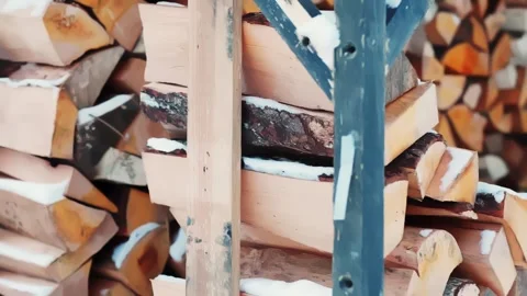 Split firewood stacked in a simple outdoor rack with snow, a rural homestead Stock Footage 327689887