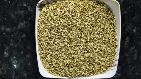 Split green gram (Moong Dal) in a white ceramic bowl on a dark marble background Видео 326021578