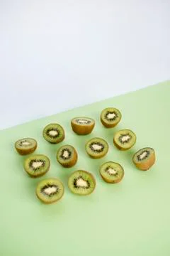 Split in half kiwi in a row and on green background Stock Photos