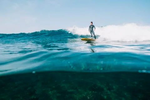 Split image of a female surfer in wetsuit surfing a small wave Foto stock