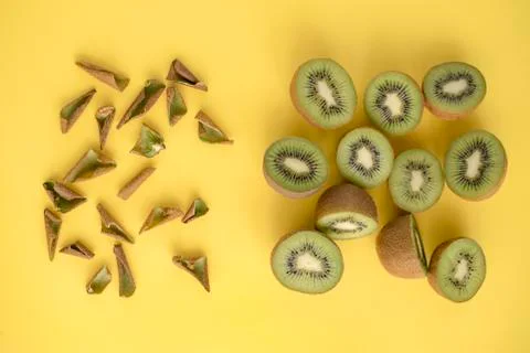 Split kiwi in half and peel them separately on yellow background Stock Photos