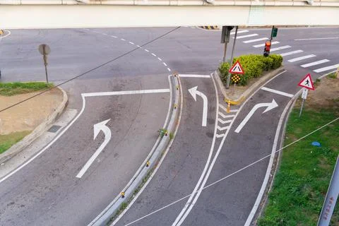Split Lane Arrows and Red Signal Beneath Overpass at Urban Road Junction Stock Photos