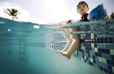 Split level of boy at the edge of pool with legs in water Foto stock