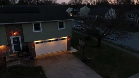 Split level home in USA. American flag and two car garage with lights on Video stock 239368103