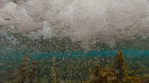 Split level of large, foaming waves rushing on shallow coral reef cowered brown Video stock 316828423