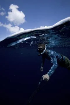 A split level shot of a diver holding onto drift line  beneath the blue waters Foto stock