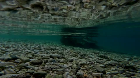 Split Level Shot Of Pebble Beach And Underwater Rocks With Clear Blue Sky And Stock Footage 324699606