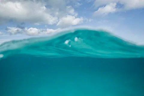 A split level shot of turquoise ocean water and clouds in a blue sky Foto stock