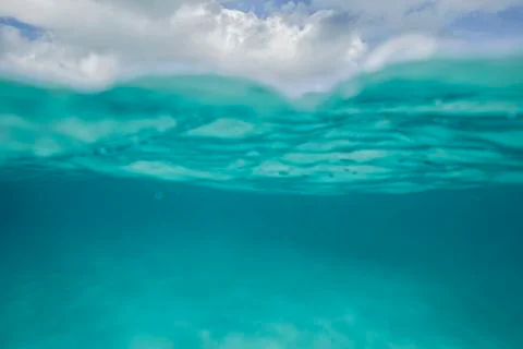 A split level shot of turquoise ocean water and clouds in a blue sky Foto stock