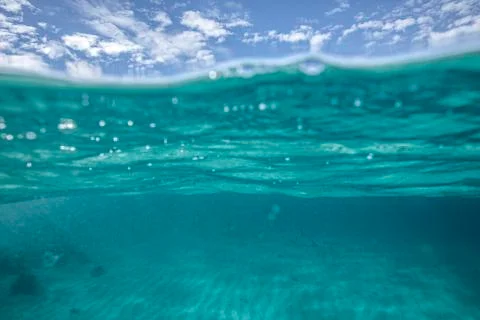 A split level shot of turquoise ocean water and clouds in a blue sky Foto stock