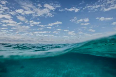 A split level shot of turquoise ocean water and clouds in a blue sky Foto stock