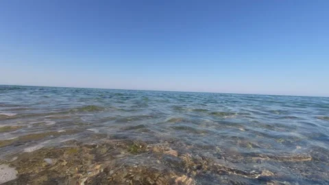 Split-level video of gentle sea waves with a clear view of underwater pebbles Stock Footage 313810576