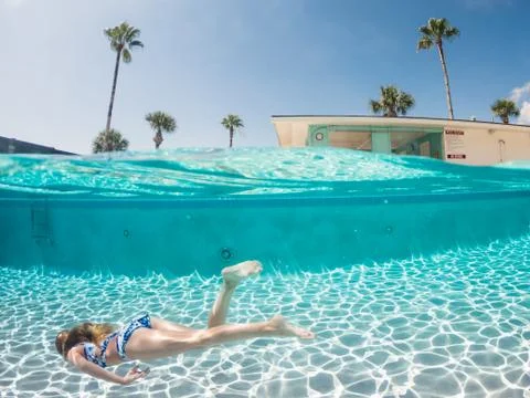 Split Level Viewpoint of Young Girl Swimming Underwater in a Pool Foto stock