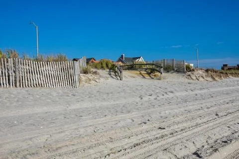 Split rail fence lining a pathway over sand dunes and high grass entering a w Foto stock