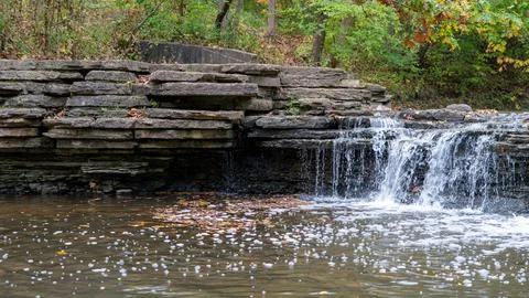 Split Scene Serenity: Waterfall Flowing Beside Rocky Formation Stock Photos