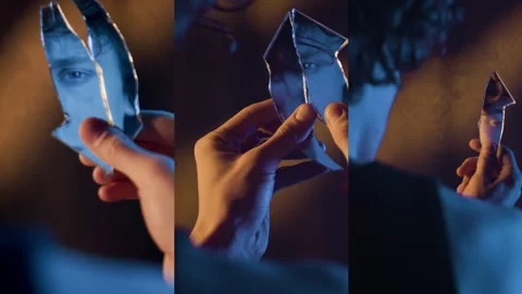 Split Screen of Mirror Reflection of Angry Man Looking at Camera Holding Shard 動画素材 303622252