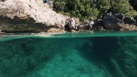 Split shot of rocky coast over under half underwater view of clear sea 스톡 동영상 338180928
