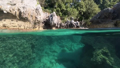 Split shot of rocky coast over under half underwater view of clear sea 스톡 동영상 338181034