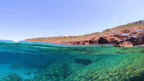 Split underwater view of a rocky shore in slow motion. Sardinia, Italy Video stock 285740006