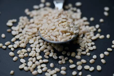 Split Urad Dal Held in Spoon, Angled Top View Food Macro Shot on Dark Defoc.. Foto stock