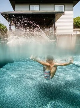 Split view of a 7 years old boy jumping in a pool at home Stock Photos