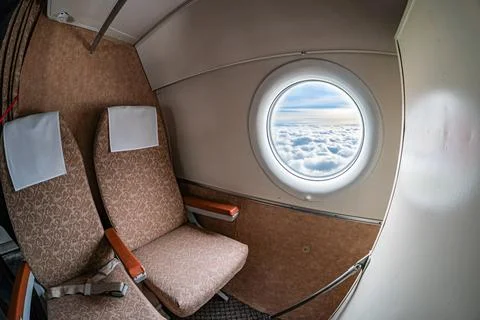 A split view of an airplane cabin, showing beige seats with dark headrests .. Stock Photos