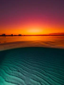 Split view with bright sunset and underwater sandy bottom. Stock Photos