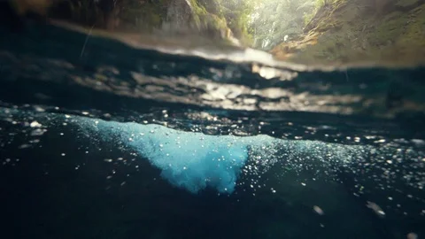 Split view half over and under a waterfall, with water foams and bubbles. Stock Footage 122574390