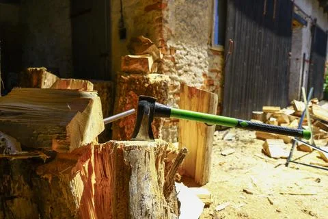 Splitting axe resting on chopping block surrounded by stacked firewood Stock Photos