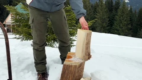 Splitting dry wooden logs with sharp axe on snowy chopping block Stock Footage 336010318