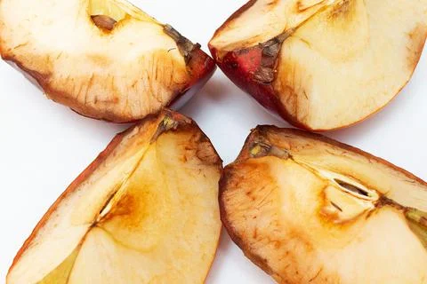 Spoiled apples close-up on a white background. Dark fruit pulp. Stock Photos